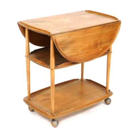 An Ercol light elm trolley, with a galleried drop front top, above two further tiers, united by turned legs, on castors, 75cm high, 74cm wide, 45cm deep, 91.5cm extended.