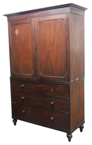 An early 19thC mahogany linen press, the outswept pediment over a pair of panelled doors opening to reveal four slides, the lower section with two short over two long drawers, raised on turned feet, 225cm high, 138cm wide, 55.5cm deep.