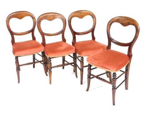 A set of four Victorian mahogany balloon back dining chairs, with overstuffed red fabric seats, raised on turned legs.