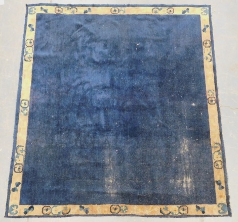 A Chinese blue ground rug, with a pale brown border, decorated with floral symbols, bats, etc.,188cm x 170cm. (AF)