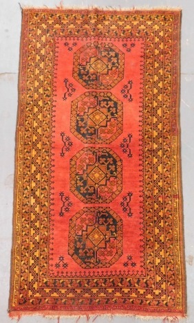 A Balouch red ground rug, with floral central medallions, within repeating foliate and geometric borders, 200cm x 106cm.