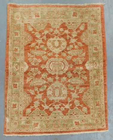 A Pakistani orange ground prayer rug, decorated with flowers and leaves within repeating floral borders, 120cm x 93cm.