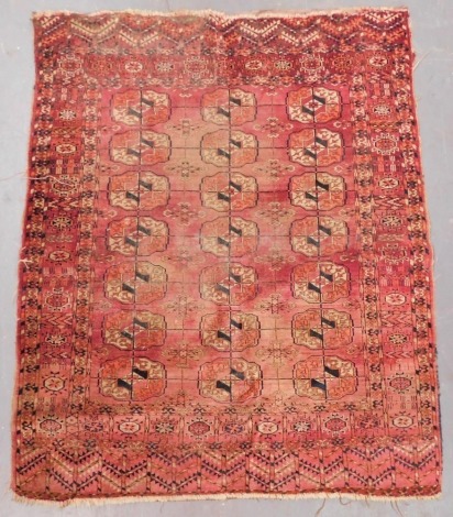 A Turkomen Tekke red ground rug, decorated with three rows of seven medallions, within repeating floral and geometric borders, 140cm x 112cm.