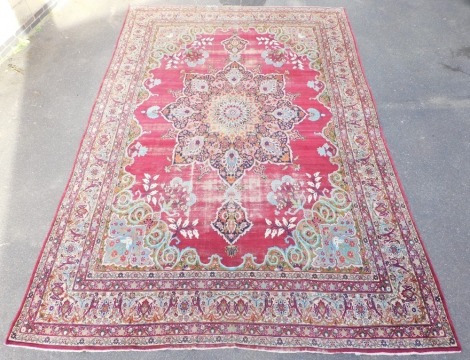 A Persian Mashed red ground rug, with a floral and foliate central medallion, further flowers and scrolling leaves, within repeating floral and foliate borders, 490cm x 330cm.