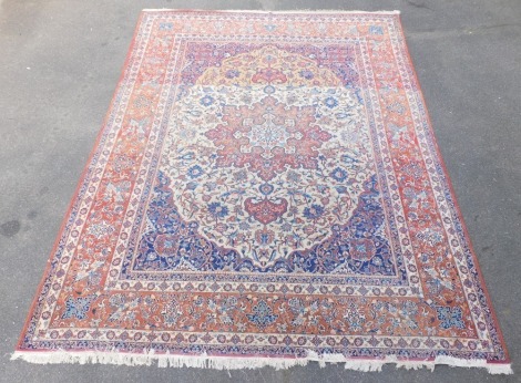 A Persian Heriz cream and blue ground rug, decorated with a central geometric and floral medallion, against a ground of further flowers and scrolling leaves, within repeating floral and foliate borders, 400cm x 312cm.