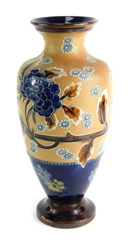 A Doulton Lambeth ovoid stoneware vase, of tapered form, decorated with tube lined flower head sprays and foliage in blue and brown, above a blue glazed band with flower heads, on tapered circular foot with brown treacle glazed, impressed marks to the bas