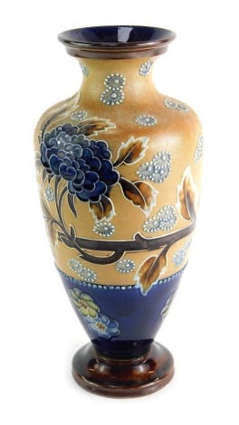 A Doulton Lambeth ovoid stoneware vase, of tapered form, decorated with tube lined flower head sprays and foliage in blue and brown, above a blue glazed band with flower heads, on tapered circular foot with brown treacle glazed, impressed marks to the bas