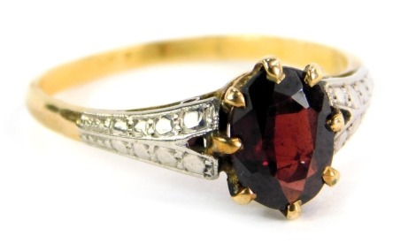 A dress ring, with central oval garnet, on V splayed white gold shoulders, on a yellow metal band, stamped 9ct, ring size P, 2.6g all in.