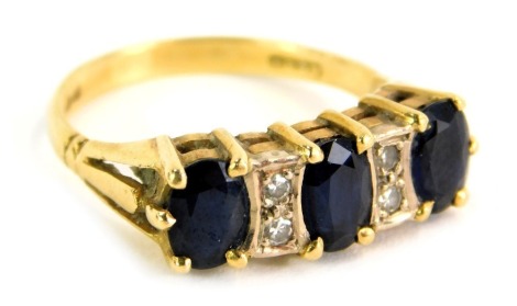 An 18ct gold sapphire and diamond gypsy ring, the panel set with three oval sapphires and inset with two tiny diamonds, each in claw setting, ring size M, 4.3g all in.