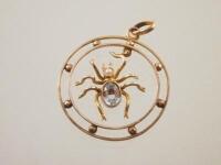 An Edwardian bi-colour metal pendant with seed pearl and aquamarine set spider suspended in the cent