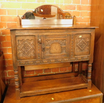 An oak side table, with two central cupboard and two carved panels, on stiles.