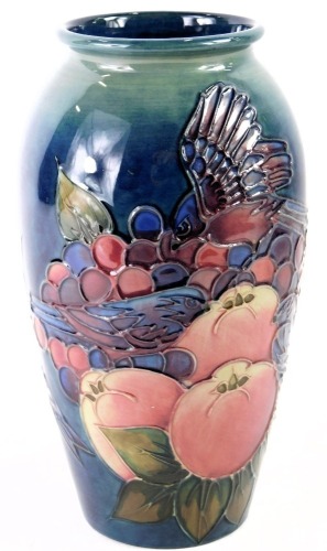 A William Moorcroft ovoid vase, on a blue ground, decorated with finches, fruits and berries, signed and stamped to underside, 19cm high.