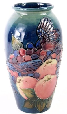 A William Moorcroft ovoid vase, on a blue ground, decorated with finches, fruits and berries, signed and stamped to underside, 19cm high.