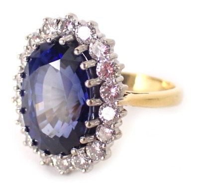 A sapphire and diamond cluster ring, the central sapphire 13.6mm x 9.6mm x 6.8mm, surrounded by diamonds each approx 0.08ct, in a white gold setting on a yellow metal band, unmarked, ring size L, 9g all in.