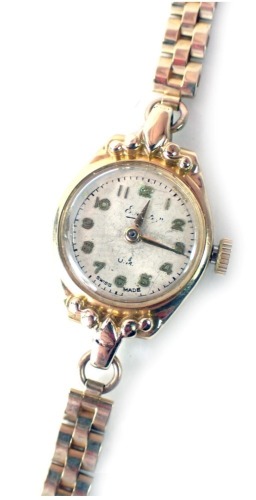 An Everite 9ct gold ladies wristwatch, with a silvered watch head in yellow metal casing, 1.5cm diameter, on three bar bracelet, 12.6g all in.