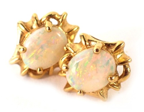 A pair of opal stud earrings, each with oval opal with outer abstract flow border, on single pin back with butterfly backs, yellow metal unmarked, butterfly backs stamped 750, 5.6g all in, boxed.