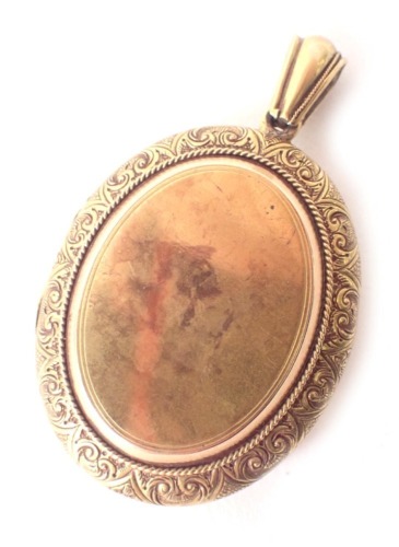 An Edwardian pinchbeck oval locket, with arched top and scroll outer border with a vacant shield, 13.4g all in. (AF)