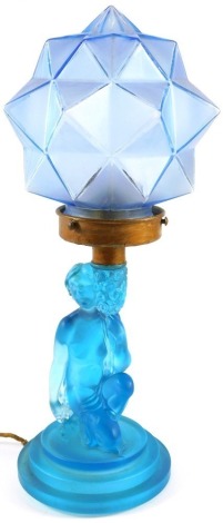 An Art Deco style frosted blue glass table lamp, of figure holding vase of flowers, on triple stepped foot, 26cm high, and a later blue triangle cut shade, 17cm high. (2)