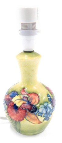 A Moorcroft table lamp, on a green and yellow ground, decorated with pink and purple flowers, stamped to underside, 24cm high.