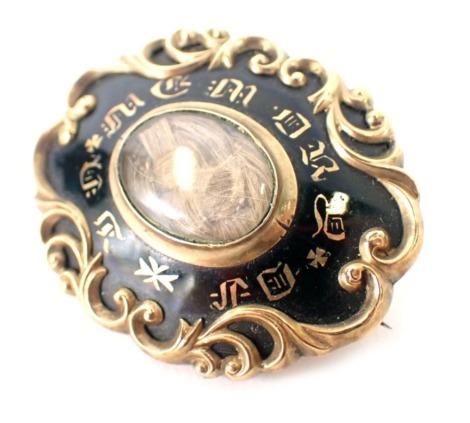 A Victorian memorial brooch, with black enamel front and central locket, inscribed in memory of, in a yellow metal casing with scroll decoration on single pin back, 3.5cm diameter, 9.6g all in.