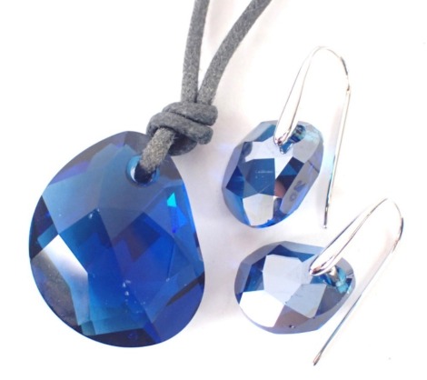 A Swarovski crystal jewellery set, comprising pendant and matching earrings, the blue crystal pendant on a grey cord necklace, together with a pair of matching drop earrings, with silvered finish hoops, boxed. (2)