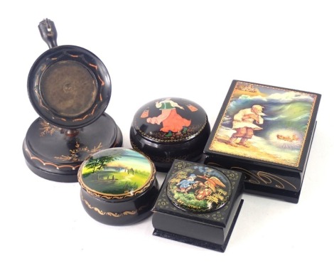 A group of Russian black lacquer painted trinket boxes, comprising two oval examples, each decorated with figures and trees, a watch stand, and a rectangular box with gentleman and angel. (5)