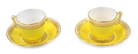 A pair of late 19thC Stevenson and Hancock Derby porcelain coffee cups and saucers, decorated with gilt bands against a canary yellow ground, painted marks.