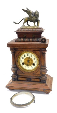 A late 19thC Hamburg Clock Company walnut cased mantel clock, circular brass dial with enamel chapter ring bearing Arabic numerals, fourteen day strike movement, the case of architectural form, with a brass St Mark's Lion to the casket shaped top, the cas