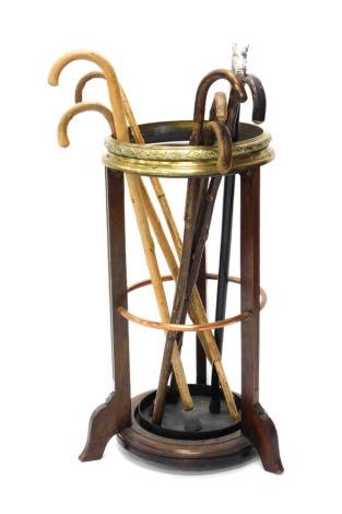 An early 20thC mahogany brass and copper banded umbrella stand, or stick stand, and various walking sticks.