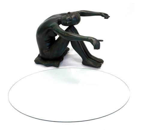 A bronzed resin coffee table, modelled in the form of a nude seated on a cushion holding the oval glass plate, glass only associated and does not currently fit.