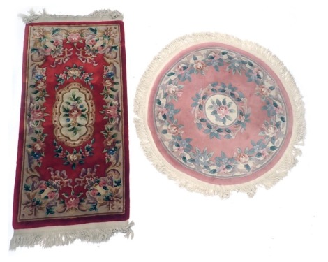 A Chinese red ground cut wool rug, with floral decoration and a circular pink ground Chinese rug, 185cm x 78cm and 110cm diameter.