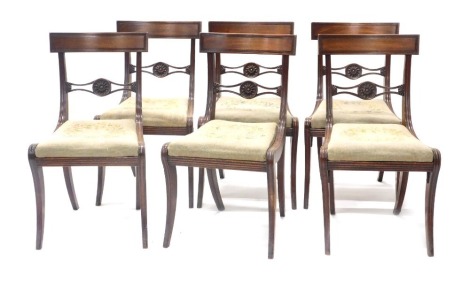 A set of six Regency mahogany dining chairs, each with a bar back with pierced support carved with patera, drop in woolwork seat, on sabre legs.