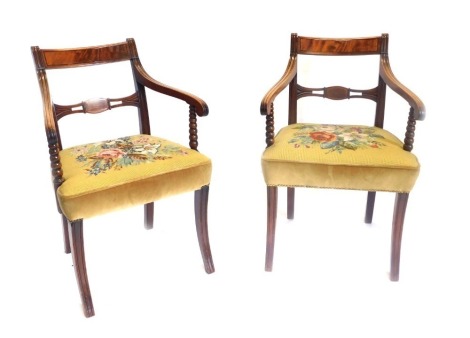 A pair of Regency mahogany open armchairs, each with a bar back, moulded arms, on bobbin turned supports, with floral upholstered gold coloured seats, on sabre legs.