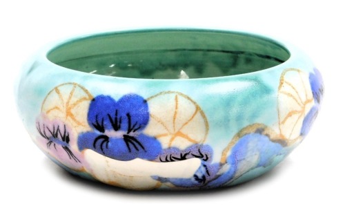 A Clarice Cliff Bizarre Inspiration pottery bowl, decorated with pansies, on a turquoise ground, printed marks, 19.5cm wide. (AF)