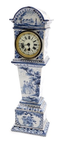 A 19thC Delft ware blue and white miniature long case clock, circular enamel dial bearing Roman and Arabic numerals, thirty hour movement, the case hood painted with a river scene and flowers, the trunk with figures in a landscape, on a base further paint