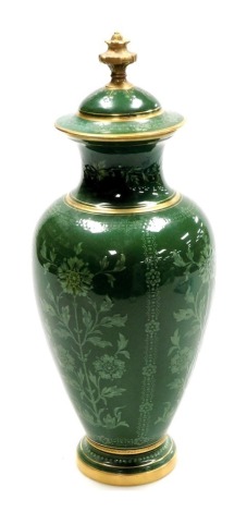 An early 20thC Coalport porcelain vase and cover, of baluster form, decorated in bas relief, with panels of stemmed flowers, on a green ground, gilt heightened, printed and painted marks, 34cm high.