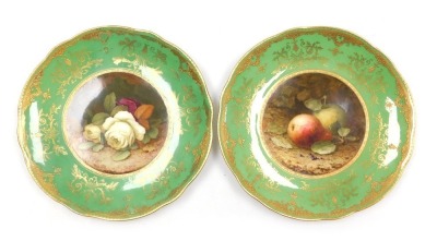 A pair of early 20thC Coalport porcelain cabinet plates, painted by F H Chivers, with fruit, and roses by P Howard, both against a green ground, gilt heightened, printed marks. (AF)