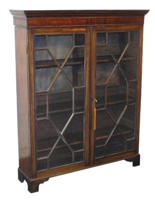 A George III style mahogany bookcase, the outswept pediment over a pair of astragal glazed doors, enclosing three shelves, raised on bracket feet, 143cm high, 114cm wide, 31cm deep.