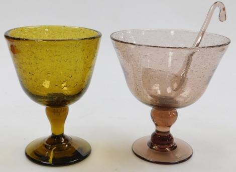 A 20thC Continental amethyst glass punch bowl, with ladle, raised on an hour glass stem, 25cm high, together with an amber glass pedestal vase, 26cm high. (2)