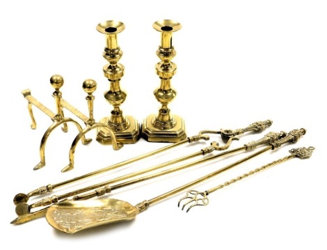 A set of three Victorian style brass fire irons, comprising pair of coal tongs, poker and shovel, pair of andirons, toasting fork, and a pair of brass candlesticks, 31cm high. (8)