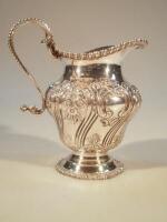 A Victorian baluster jug with repousse decoration of swirling gadroon and scroll patterns