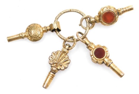 Four 19thC pinchbeck watch keys, with embossed or engraved decoration, one set with a bloodstone and a cornelian, the other set with glass on a ring suspension.