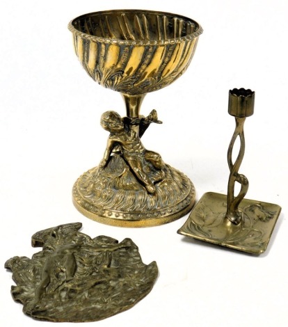 A 20thC Continental brass pedestal sweet meat dish, the bowl with semi fluted and foliate embossed decoration, raised on a putto stem, and a circular floral and foliate embossed base, 21cm high, together with an Art Nouveau style brass candlestick, and a