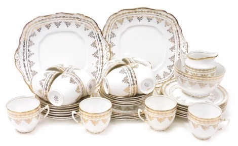 A Royal Worcester porcelain tea service, gilt decorated with scrolling flowers, within a repeating holly border, printed marks, comprising a pair of bread plates, cream jug, sugar bowl, twelve cups, saucers and tea plates.