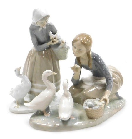 A Lladro porcelain figure group, modelled a kneeling girl feeding vegetables to ducks, on a naturalistic base, 25cm wide, and a further Lladro figure of a peasant girl, modelled standing with a duck and a basket of duckling, 22cm high. (2)