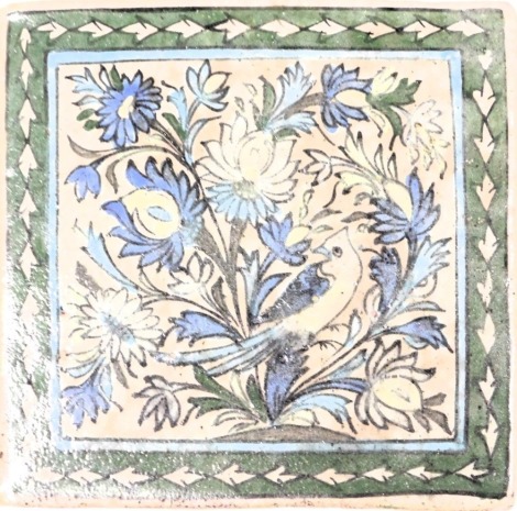 An Iznik pottery tile, painted with a bird and flowers, within a repeating leaf border, 24cm x 25cm.