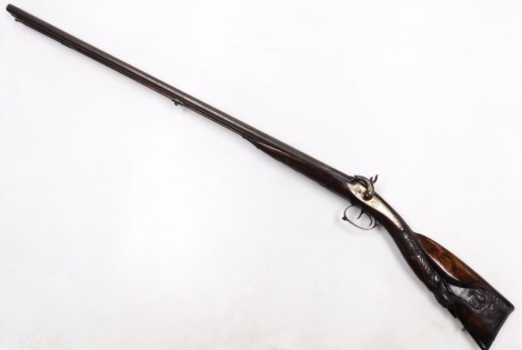 A 19thC double barrel muzzle loading percussion sporting shotgun, with ramrod, the walnut stock carved with a deer, hose, and scales, the hammers cast as wild beast's heads, the butt opening, to reveal a twin barrel compartment, barrels 82m long, gun 125c