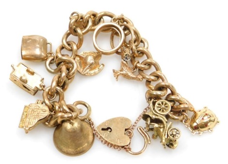 A 9ct gold curb link charm bracelet, on a heart shaped padlock clasp, with ten charms as fitted, 44.6g