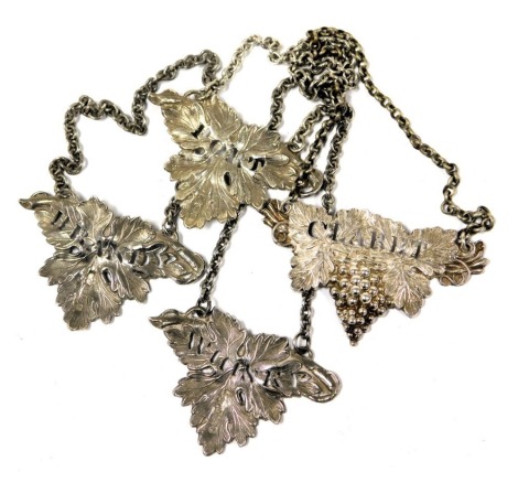 Three Elizabeth II silver decanter labels, of leaf form, impressed with Brandy, Port and Whisky, on chain link suspensions, Birmingham 1983 and 1984, and a William IV silver decanter label, embossed with vines and impressed with claret, on a chain link su