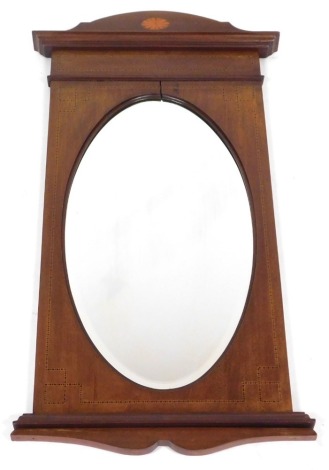 An Edwardian mahogany and inlaid wall mirror, the curved pediment with sunburst paterae inlay, above an oval bevelled glass plate, 90cm x 50cm.